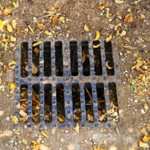 winter - dirty landscape drain with fall leaves